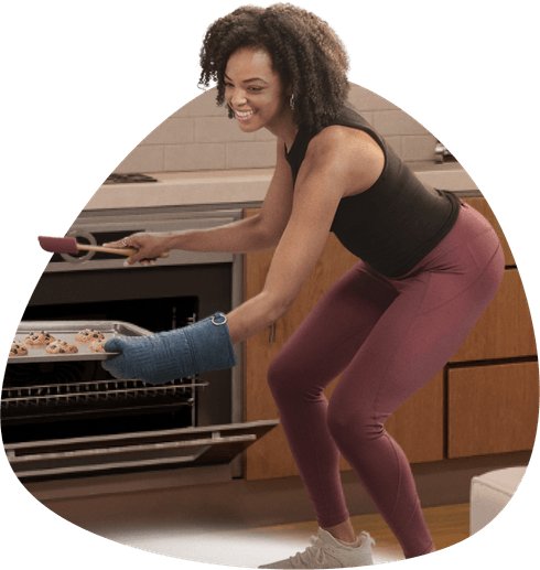 A woman pulling cookies out of the oven